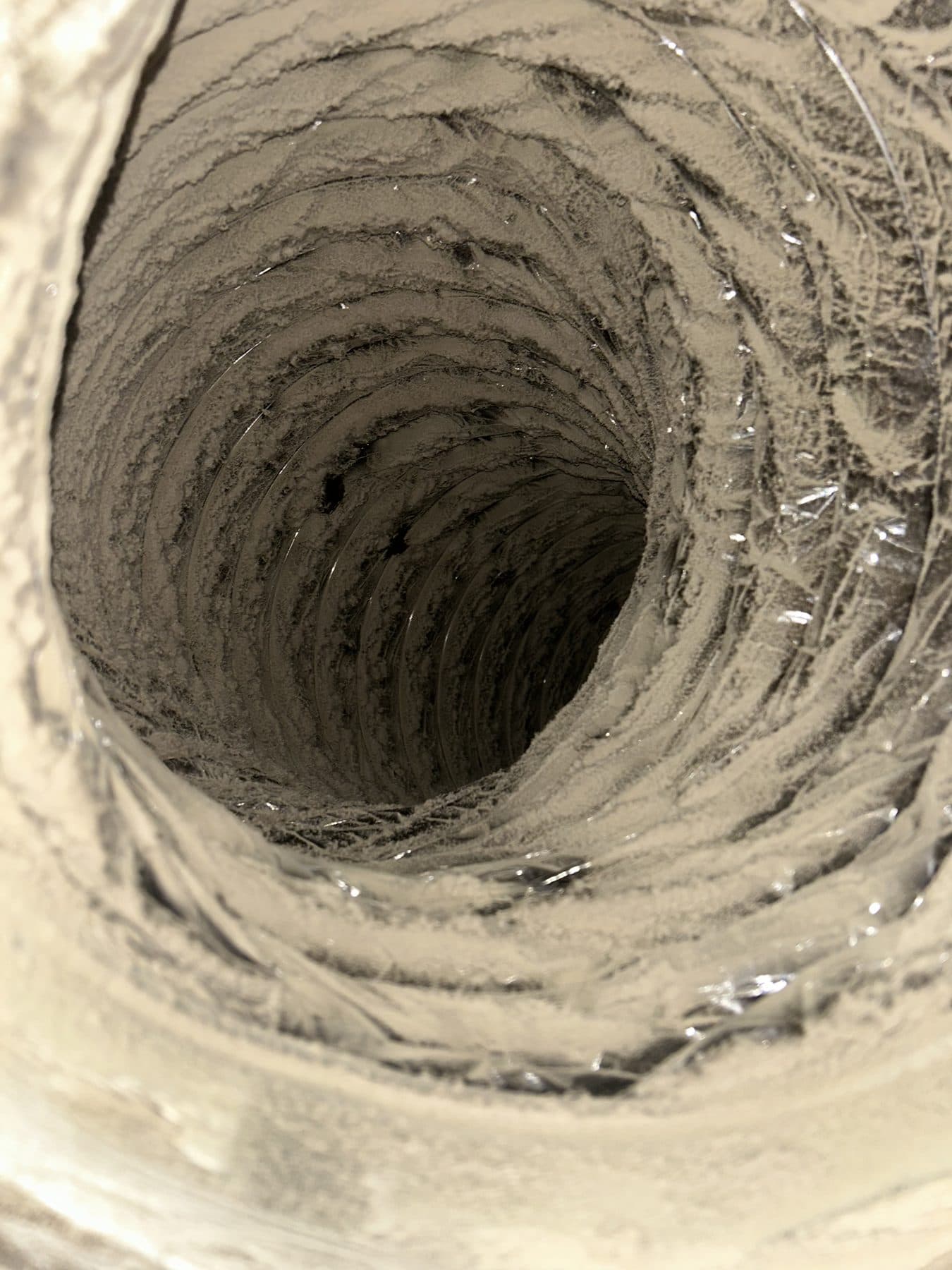 Flexible duct interior packed with pale grey dust before cleaning