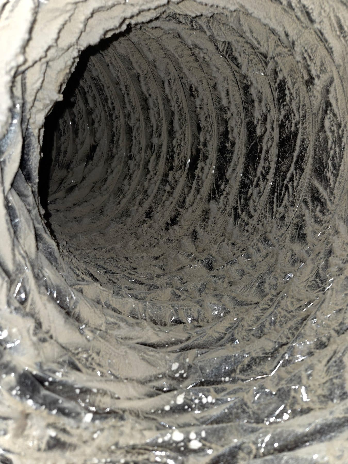 Dust layered along the interior wall of a flexible air duct before cleaning